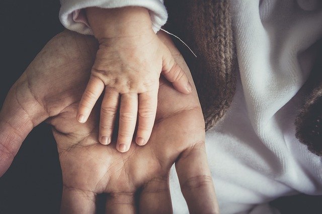 petite main de bébé posée sur main d'homme adulte paume à l'extérieur