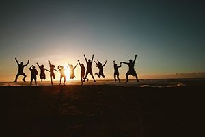 Groupe de gens qui sautent dans les airs sur la plage en signe d'esprit d'équipe