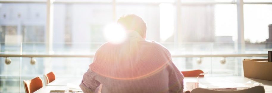Homme travaillant devant une fenêtre avec le reflet du soleil