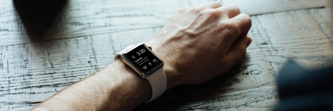Bras d'un homme posé sur une table avec une montre intelligente