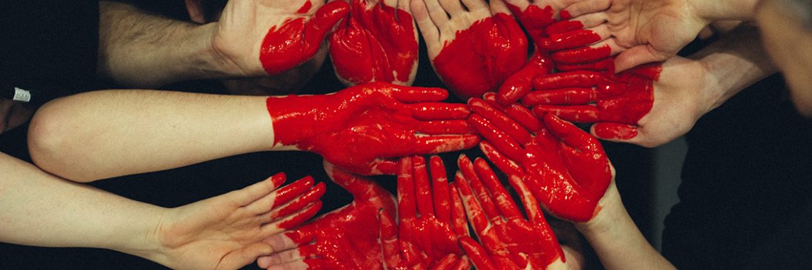 peinture rouge appliquée sur un groupe de mains pour former un coeur