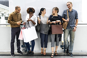 Groupe de gens debout contre un mur avec des sacs d'achat