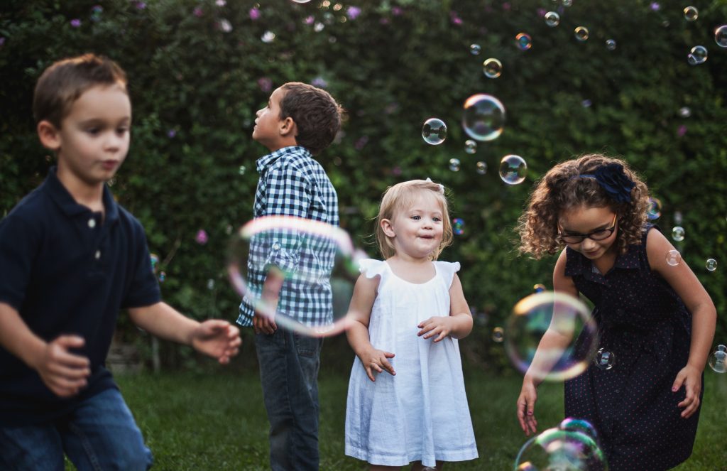4 enfants jouent avec de grosses bulles de savon
